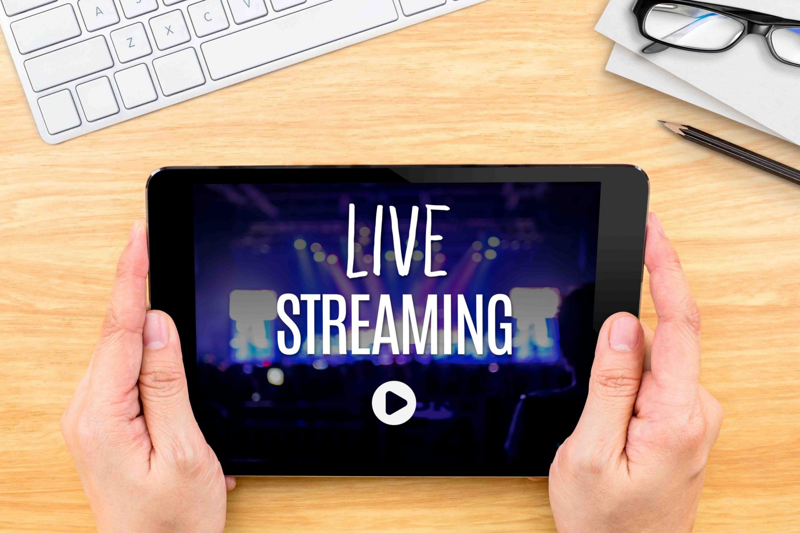 Hand holding tablet with Live Streaming word on wood table ,Inte
