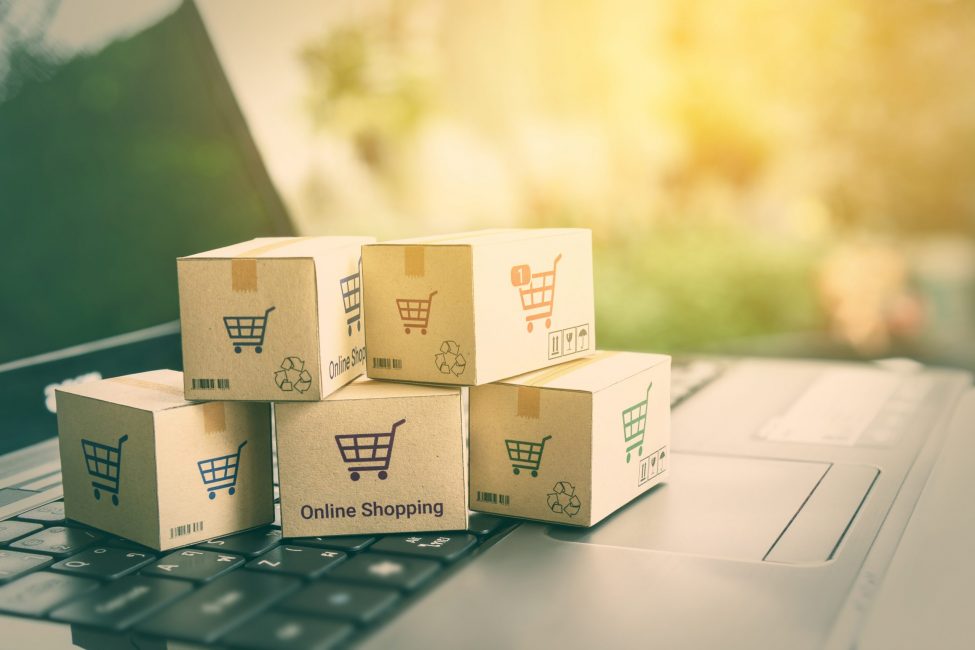 Online shopping / ecommerce and delivery service concept : Paper cartons with a shopping cart or trolley logo on a laptop keyboard, depicts customers order things from retailer sites via the internet.